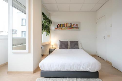 um quarto com uma cama num quarto branco em Beau studio dans le Centre de Bruxelles em Bruxelas