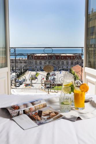 a table with a magazine and glasses of orange juice at Mediterranean Palace in Thessaloniki