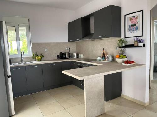 a kitchen with black cabinets and a marble counter top at Ion villa - Xirokampi in Ayiá