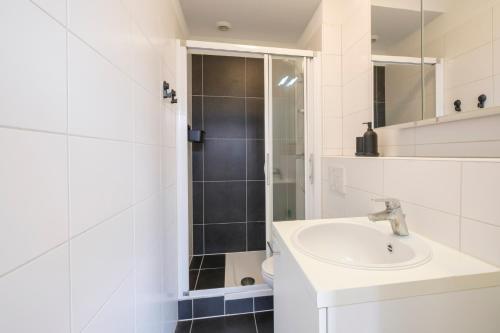 uma casa de banho branca com um lavatório e um chuveiro em Beau studio dans le Centre de Bruxelles em Bruxelas