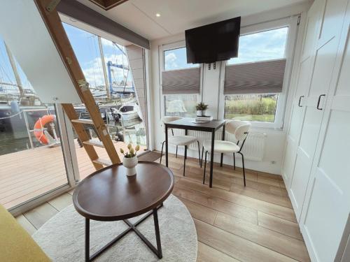 a living room with a table and chairs and a television at Tiny lake houses near the beach and centre by Weltevreden Experience in Zeewolde