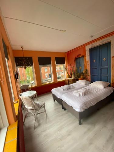 a bedroom with two beds and a chair and windows at Stee in Stad in Groningen