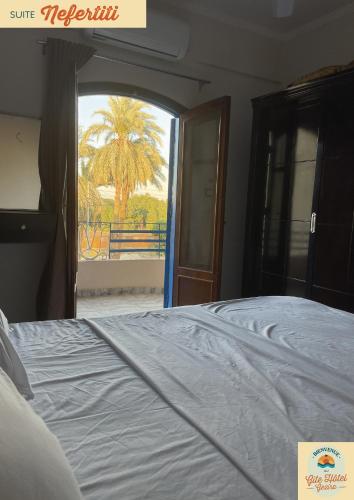 a bedroom with a bed with a view of a palm tree at Gîte Hôtel Gezira Louxor 2 in Luxor