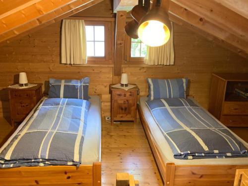 2 łóżka w pokoju z drewnianymi ścianami w obiekcie Fravgia veglia w mieście Andeer