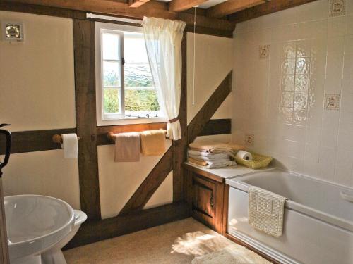 La salle de bains est pourvue d'une baignoire, d'un lavabo et d'une fenêtre. dans l'établissement Bank Cottage, à Boraston