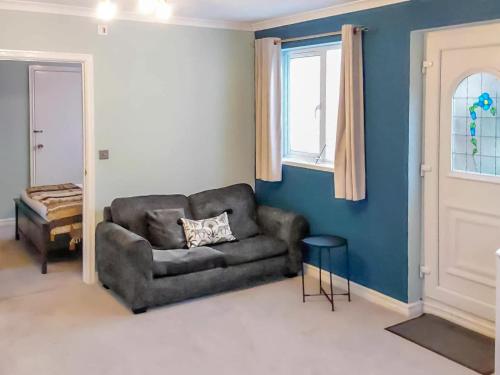 sala de estar con sofá y ventana en The Annex Cottage en Weymouth