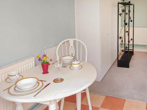 - une table blanche avec des assiettes et des verres dans l'établissement The Annex Cottage, à Weymouth