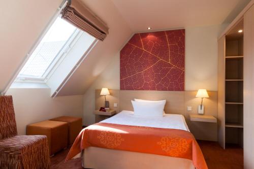 a attic bedroom with a bed and a window at Logis Hôtel Kur- und Wellnesshaus Spree Balance in Burg