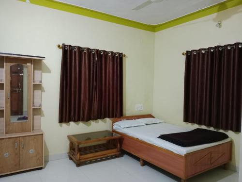 a bedroom with a bed and a dresser and curtains at Vrundavan in Panchgani
