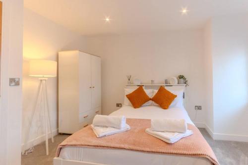 a white bedroom with a bed with orange pillows at Stylish Westgate-on-sea Haven Near Beach in Margate