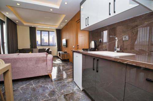 eine Küche mit einem Waschbecken und einem Sofa in einem Zimmer in der Unterkunft Evin Park Suit Lara in Aksu