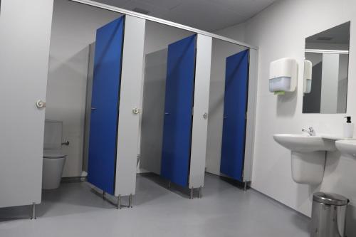 a bathroom with blue stalls with a toilet and a sink at ALBERGUE DON QUIJOTE in Arzúa
