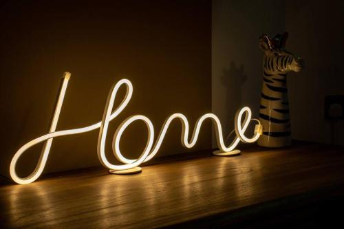 a neon sign that says love in a dark room at The Cosy House with Free Parking, Garden and Smart TV with Netflix by Yoko Property - Perfect for Contractors, Groups & Relocation in Leamington Spa