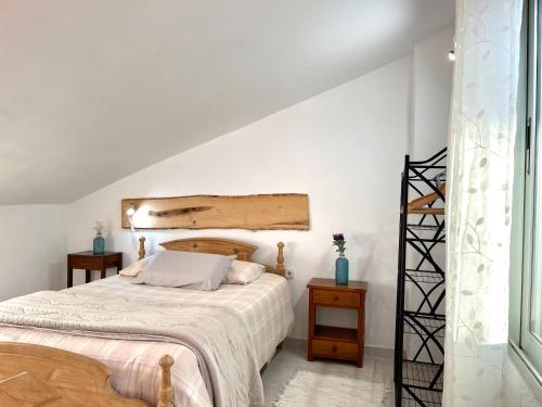 a white bedroom with a bed and a staircase at Alojamiento Turístico Casa Ela in L'Aldea