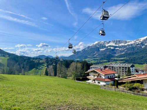 a gondola lift over a green field with mountains at Apartment Berghof Ellmau in Ellmau