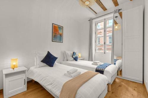 Cet hébergement comprend 2 lits dans une chambre dotée de murs blancs et d'oreillers bleus. dans l'établissement Frère Jacques - Appt situé plein centre, à Toulouse