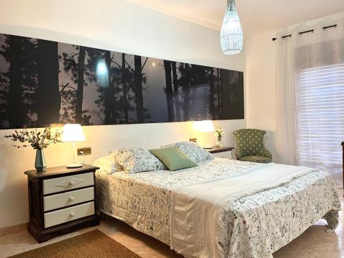 a bedroom with a bed and two tables and a chair at Alojamiento Turístico Casa Ela in L'Aldea