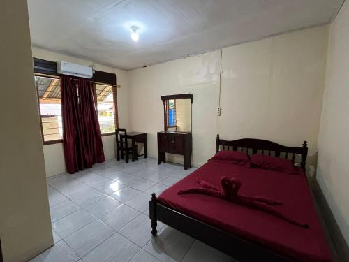 a bedroom with a bed with a red blanket at EL Homestay Bunaken in Bunaken