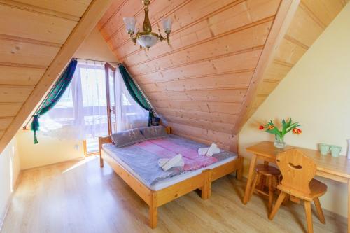 a bed in a room with a wooden ceiling at Willa Piękne Widoki in Ząb