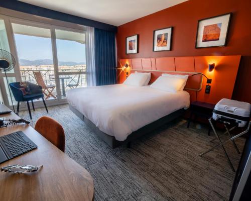 a hotel room with a bed and a desk with a laptop at Mercure Thalasso & Spa Port Fréjus in Fréjus
