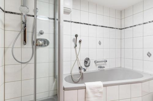 a white bathroom with a shower and a tub at Ferienwohnung zum Pavillon in Mühlenbach