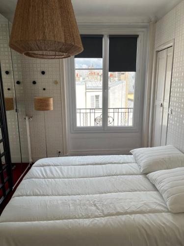 un grand lit blanc dans une chambre avec une fenêtre dans l'établissement Saint Antoine CityCosy, à Paris