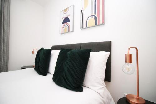 - une chambre avec un lit doté d'oreillers verts et blancs dans l'établissement Quaysideone bedroom apartment in Cardiff Bay, à Cardiff