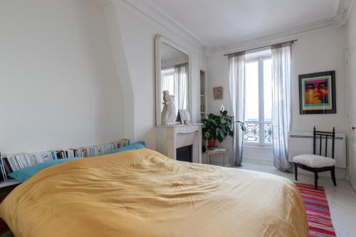 a white bedroom with a large bed and a window at Marais Magique: Exclusive Apartment in Paris in Paris