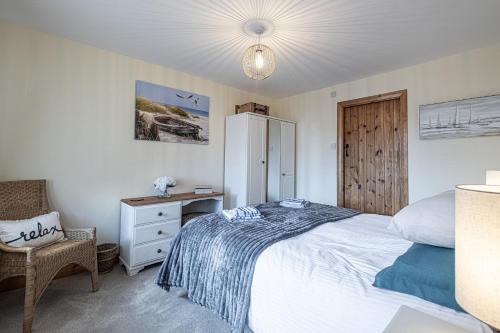 a bedroom with a bed and a desk and a chair at Penrhyn Cottage in Cemaes Bay