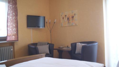 a room with two chairs and a table and a tv at Gasthof zur Burgruine in Pottenstein