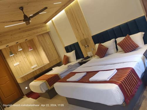 a hotel room with two beds and a ceiling fan at Gourish Resort in Mahabaleshwar