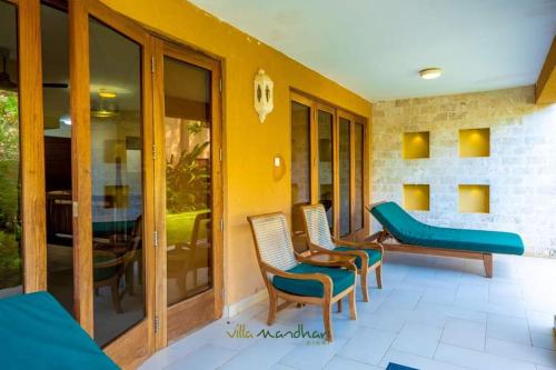 a porch with chairs and a couch and a table at Villa Mandhari - Diani Beach in Diani Beach