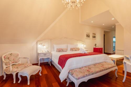 a bedroom with a large white bed and a chandelier at Pousada D'Biagy Premium in Campos do Jordão