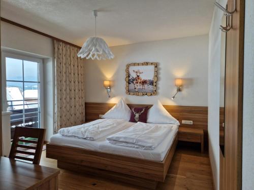 1 dormitorio con cama, mesa y lámpara de araña en Alpenhof Wängle, en Reutte