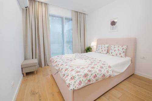a bedroom with a white bed with a floral bedspread at Promenada Puzi Place in Bucharest