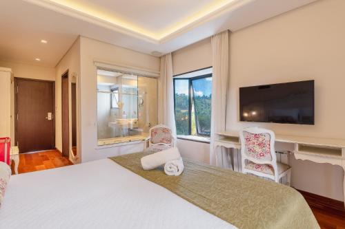 a bedroom with a large bed with two chairs and a tv at Pousada D'Biagy Premium in Campos do Jordão