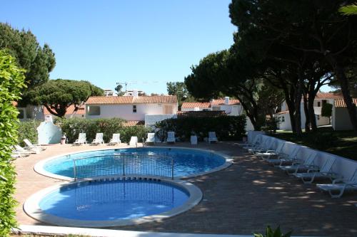 a swimming pool with chairs and a house in the background at Aldeia Da Falesia in Albufeira