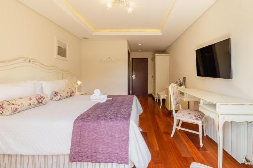a bedroom with a bed and a desk and a television at Pousada D'Biagy Premium in Campos do Jordão