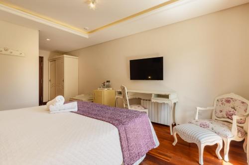 a bedroom with a white bed and two chairs at Pousada D'Biagy Premium in Campos do Jordão