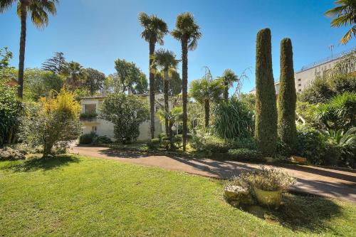 un jardin avec des palmiers et un bâtiment dans l'établissement Le Bel - Jardin - Parking - VCA, à Cannes