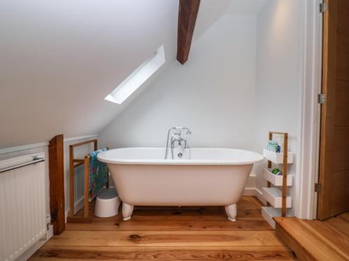 uma casa de banho com uma banheira branca num sótão em 2 Engine House em Lyme Regis