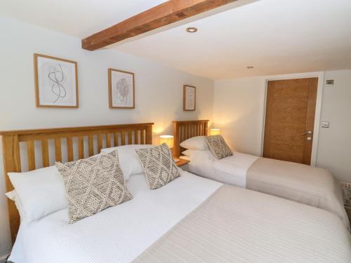 Duas camas num quarto com paredes brancas em 2 Engine House em Lyme Regis