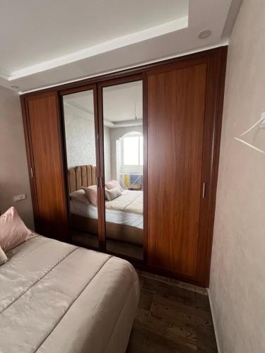 a bedroom with a bed and a large mirror at Appartement Dar Bouazza Tamaris Casablanca Airport AquaParc Fibre Orange Wifi Parking Security in Dar Bouazza