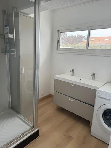 une salle de bain avec un lavabo et une machine à laver dans l'établissement Villa vue direct océan 21 couchages, à Hourtin