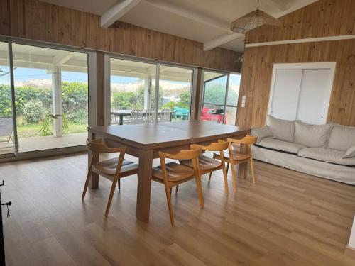 une salle à manger avec une table, des chaises et un canapé dans l'établissement Villa vue direct océan 21 couchages, à Hourtin