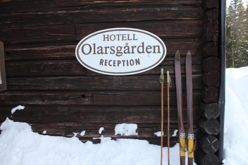 a sign on the side of a wooden cabin with skis at Olarsgården Hotell in Lindvallen