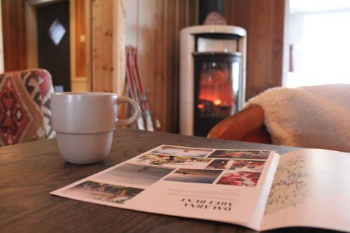 a coffee cup and a magazine on a table with a book at Olarsgården Hotell in Lindvallen