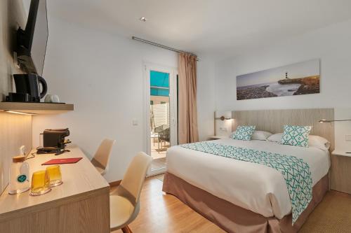 Habitación de hotel con cama grande y escritorio. en Hotel Colonial, en Colonia de Sant Jordi