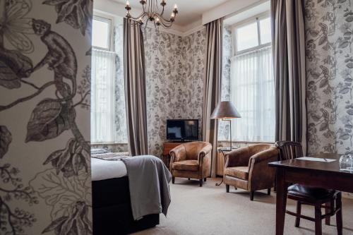 Cette chambre comprend un lit, un bureau et des chaises. dans l'établissement Kasteel Engelenburg, à Brummen