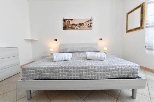 een witte slaapkamer met een groot bed met 2 kussens bij Il Mosaico Apartment in Oristano